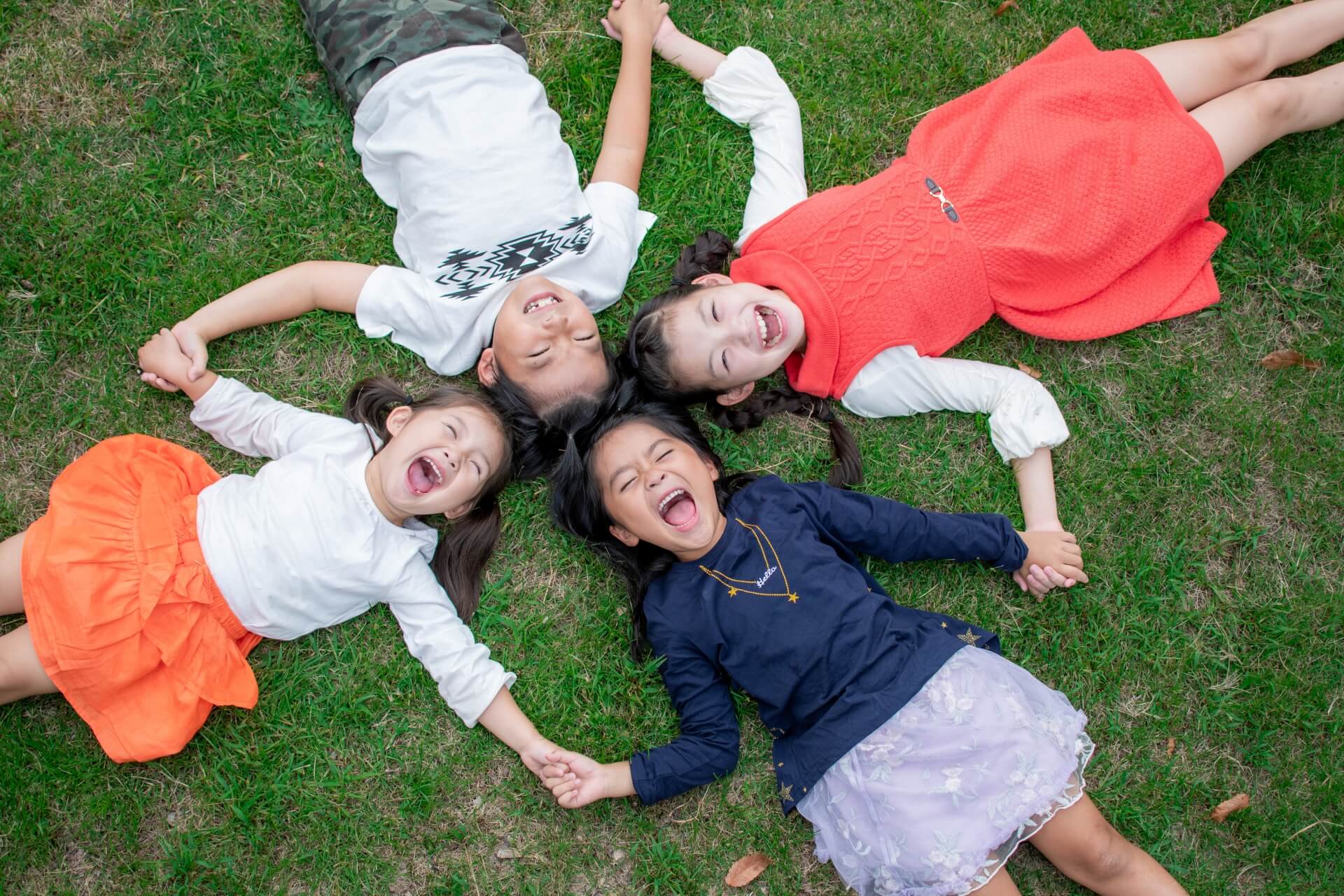 子どもたちが笑顔で輪になって手を繋いでいる写真